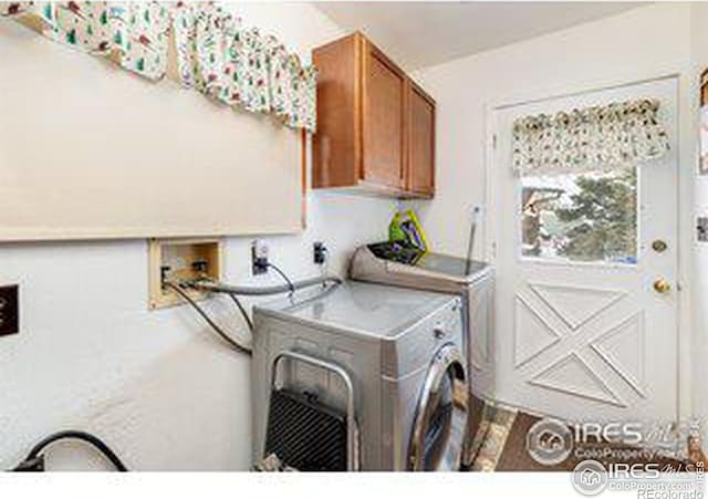 clothes washing area with washing machine and dryer and cabinets