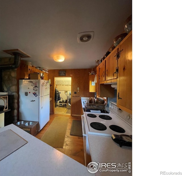 kitchen featuring white fridge, a wood stove, light wood-type flooring, wooden walls, and washer / clothes dryer