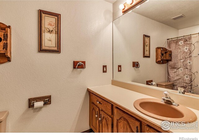 bathroom featuring vanity, a textured ceiling, and toilet