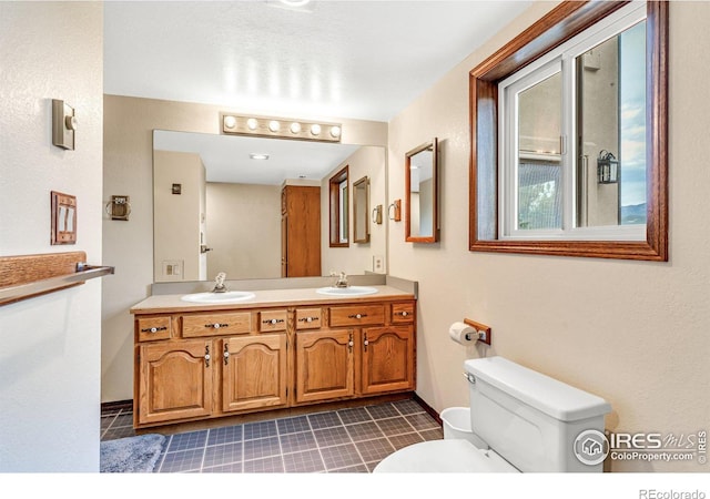 bathroom featuring dual vanity, toilet, and tile patterned floors