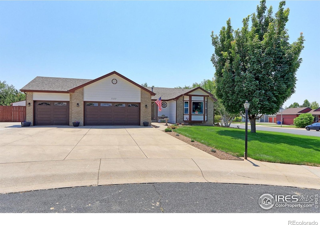 view of front of home featuring a garage, driveway, a front yard, and brick siding