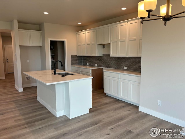 kitchen with light hardwood / wood-style flooring, sink, an island with sink, and white cabinets