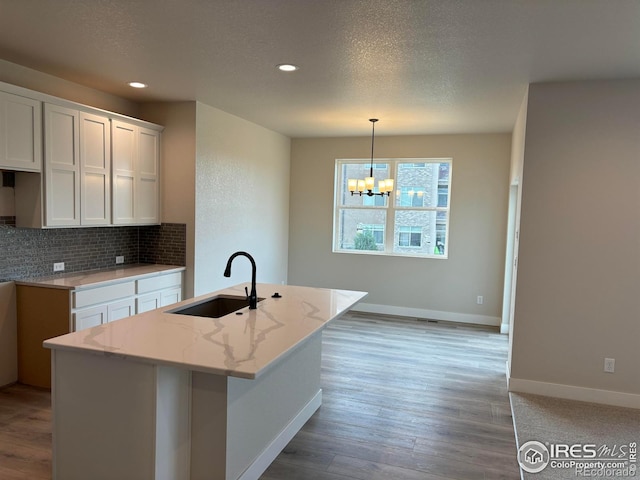 kitchen featuring white cabinetry, sink, light wood-type flooring, and hanging light fixtures