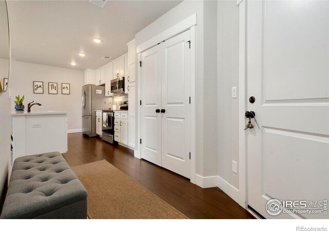 interior space with white cabinets, stainless steel appliances, dark wood-type flooring, and sink