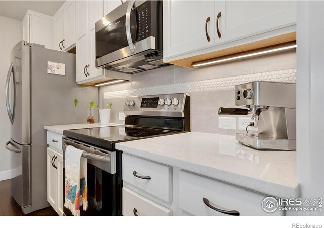 kitchen featuring white cabinets, appliances with stainless steel finishes, and light stone counters