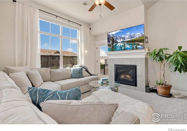 carpeted living room with ceiling fan and a fireplace