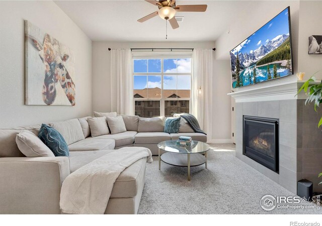 living room with light colored carpet, ceiling fan, and a tiled fireplace