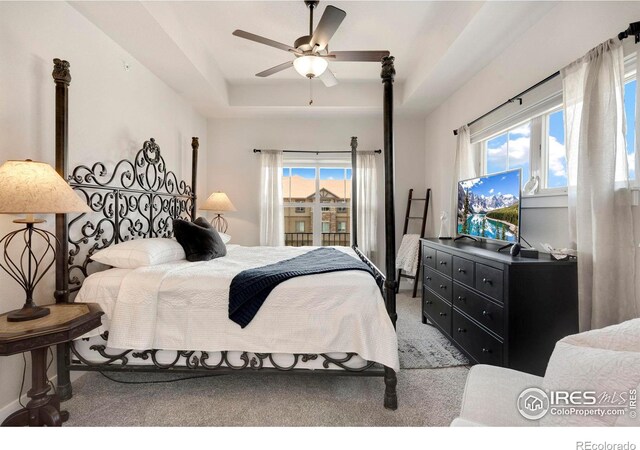 bedroom featuring a tray ceiling, ceiling fan, and light carpet