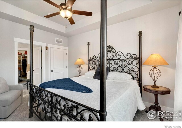 carpeted bedroom with a tray ceiling and ceiling fan