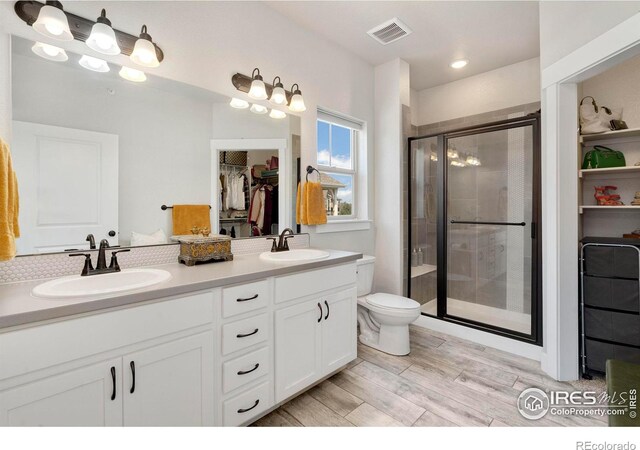 bathroom featuring vanity, wood-type flooring, a shower with shower door, and toilet