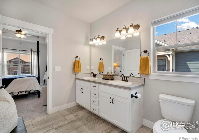 bathroom with wood-type flooring, vanity, toilet, and ceiling fan