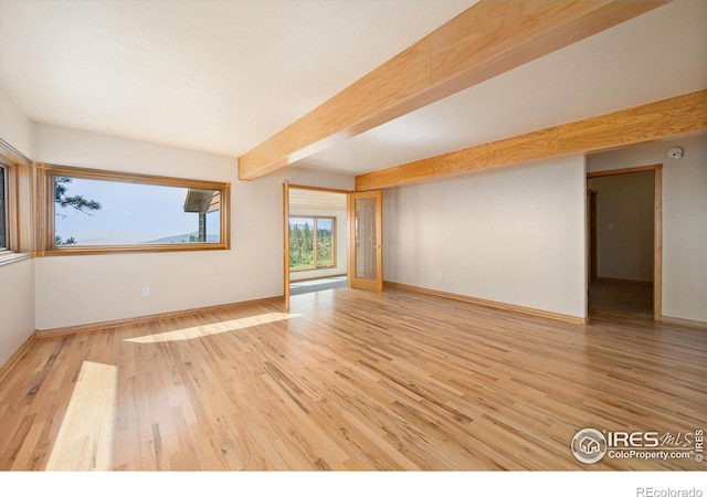 empty room featuring beam ceiling and light wood-type flooring