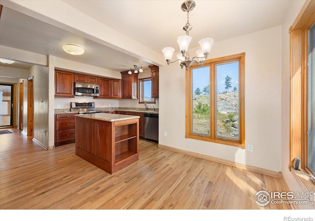 kitchen featuring pendant lighting, an inviting chandelier, a center island, light hardwood / wood-style floors, and appliances with stainless steel finishes