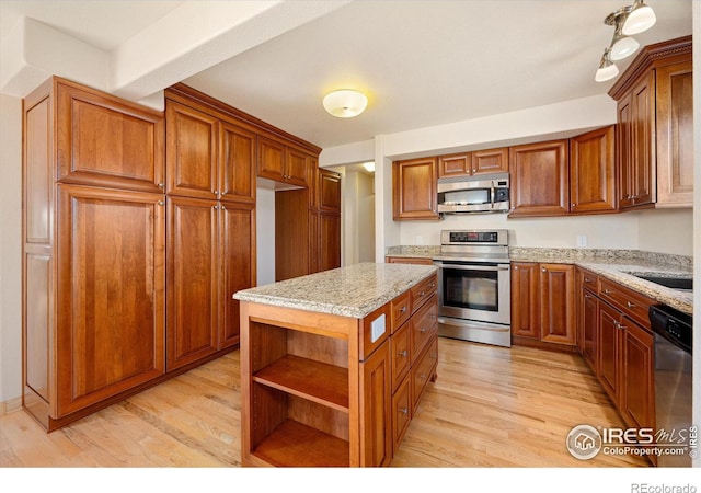 kitchen with a kitchen island, appliances with stainless steel finishes, track lighting, and light hardwood / wood-style floors