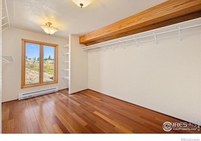 spacious closet with a baseboard radiator and hardwood / wood-style floors