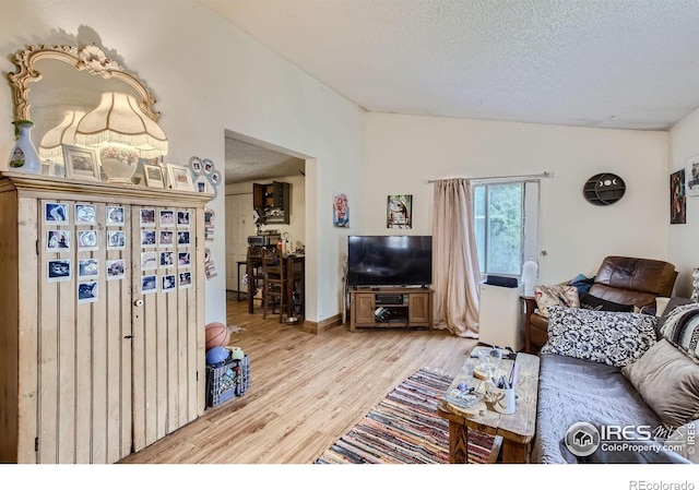 living room featuring light hardwood / wood-style floors, vaulted ceiling, and a textured ceiling