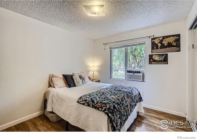 bedroom with a textured ceiling and dark hardwood / wood-style floors