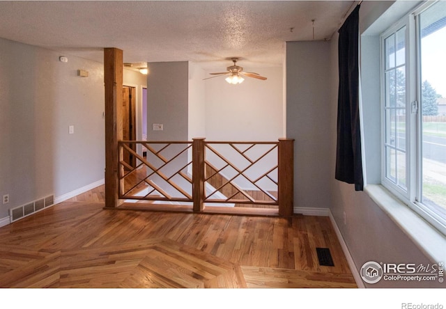 unfurnished room featuring ceiling fan, parquet flooring, and a textured ceiling