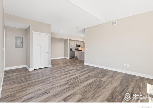 unfurnished living room with hardwood / wood-style floors and electric panel