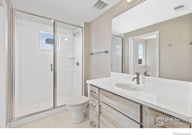 bathroom with a wealth of natural light, vanity, tile patterned flooring, and toilet