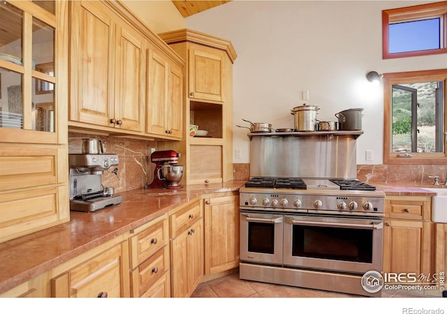 kitchen featuring double oven range, light brown cabinets, decorative backsplash, tile counters, and light tile patterned flooring