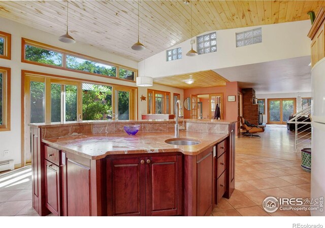 kitchen featuring a center island with sink, hanging light fixtures, sink, and wooden ceiling