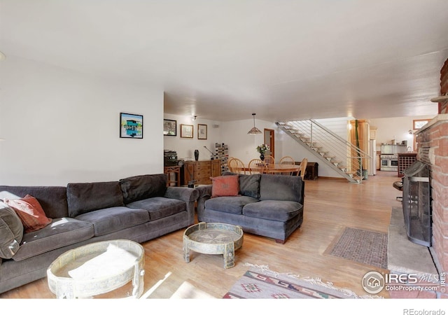 living room featuring brick wall, light hardwood / wood-style flooring, and a brick fireplace