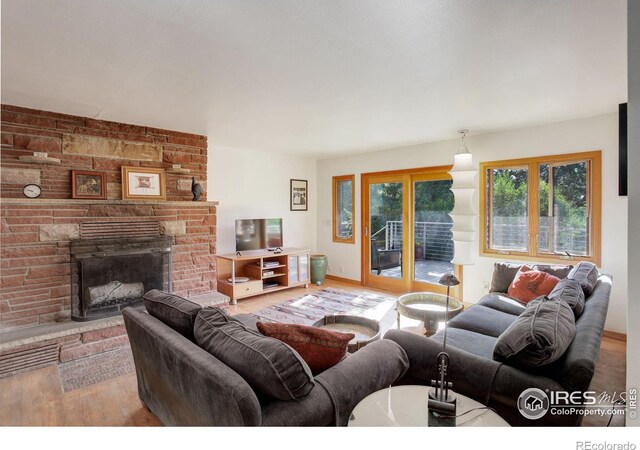 living room featuring brick wall, a brick fireplace, and hardwood / wood-style floors