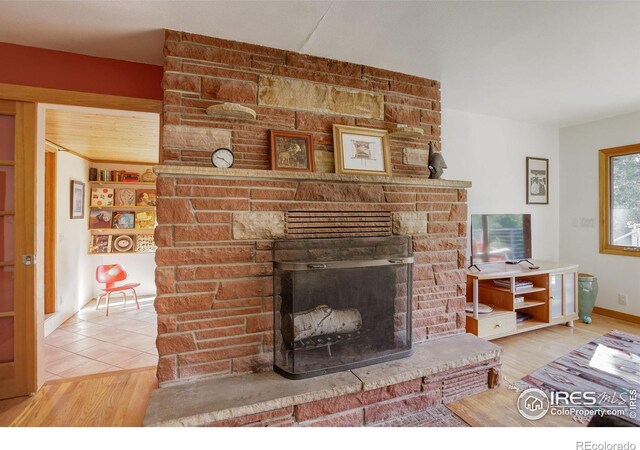 living room featuring a fireplace, wood-type flooring, and brick wall