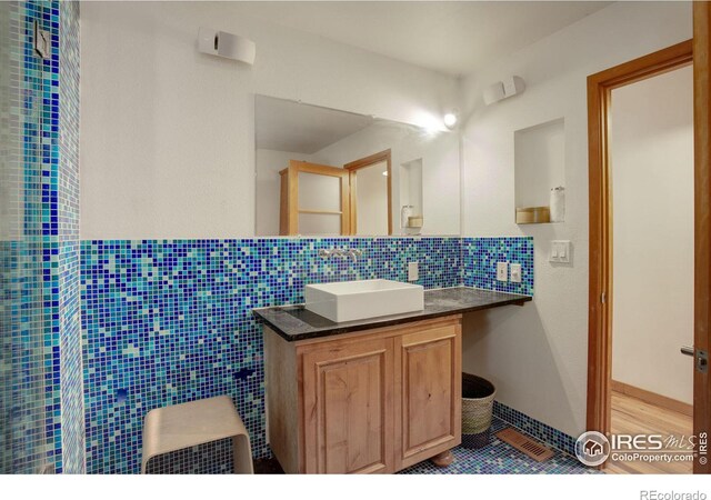 bathroom with vanity, tasteful backsplash, and tile walls