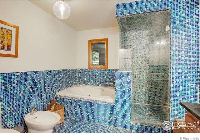 bathroom featuring a bidet, vanity, tile walls, and a relaxing tiled tub