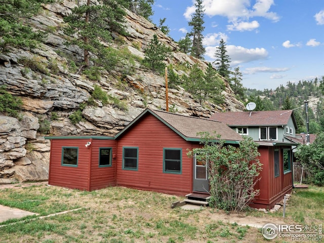 rear view of property with entry steps and a yard