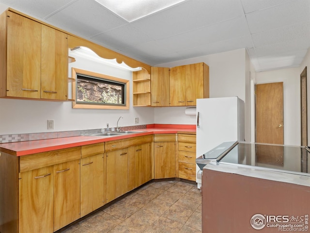 kitchen featuring a paneled ceiling, light countertops, a sink, and open shelves