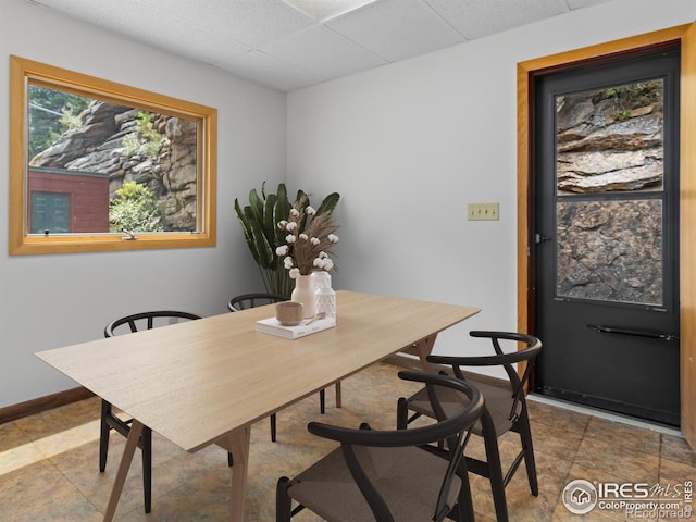 dining space featuring a paneled ceiling and baseboards