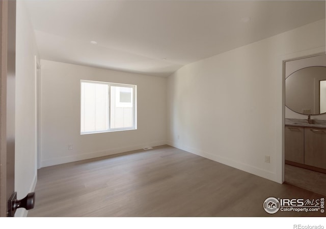 unfurnished room featuring light wood-type flooring and lofted ceiling