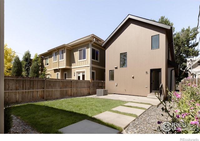 rear view of house featuring a lawn, central AC, and a patio area