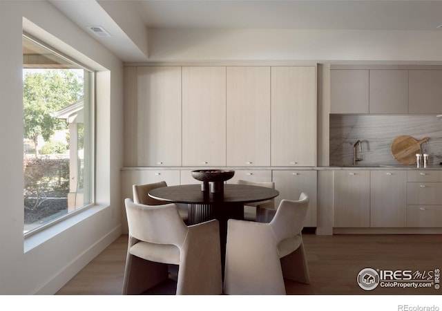 dining room with light wood-type flooring, sink, and a wealth of natural light