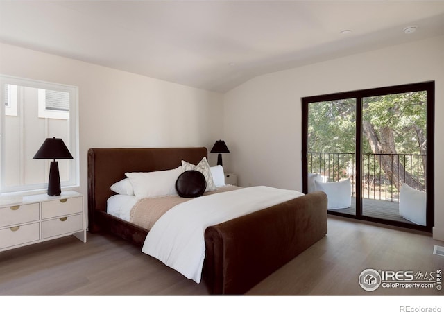 bedroom featuring access to outside, vaulted ceiling, and dark hardwood / wood-style flooring