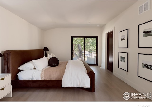 bedroom with lofted ceiling, hardwood / wood-style floors, and access to exterior