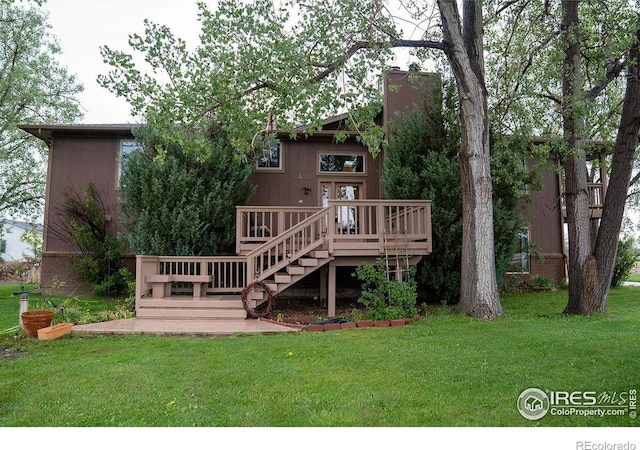 rear view of house featuring a deck and a lawn