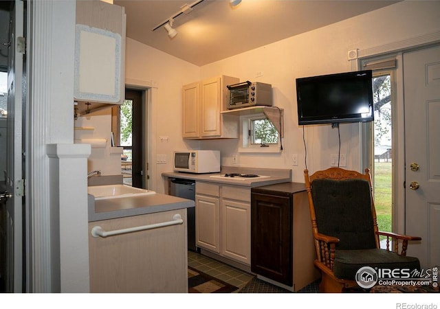 kitchen with lofted ceiling, sink, track lighting, white appliances, and white cabinets