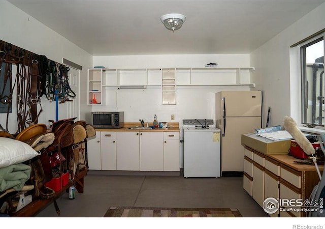 kitchen with sink, white cabinetry, washer / clothes dryer, and white refrigerator