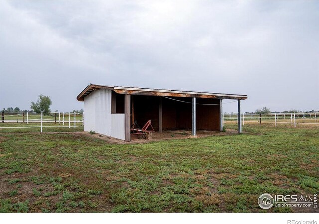 exterior space with a rural view, an outdoor structure, and a lawn