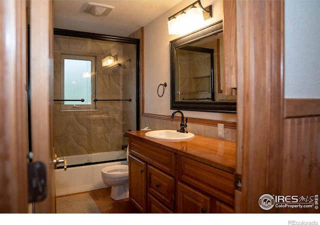 full bathroom featuring vanity, toilet, and combined bath / shower with glass door