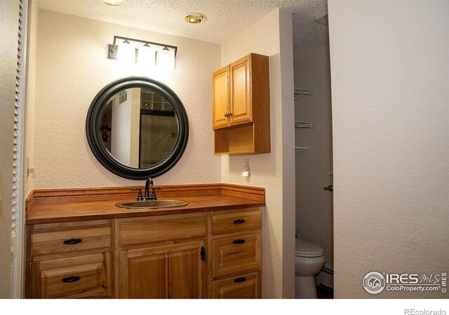 bathroom featuring a textured ceiling, a baseboard heating unit, vanity, and toilet