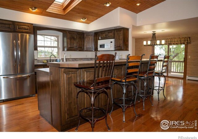 kitchen featuring wooden ceiling, lofted ceiling with skylight, stainless steel refrigerator, and a healthy amount of sunlight