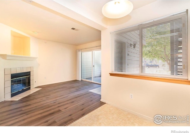 unfurnished living room featuring hardwood / wood-style floors and a tile fireplace