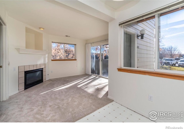 unfurnished living room with light carpet and a tile fireplace