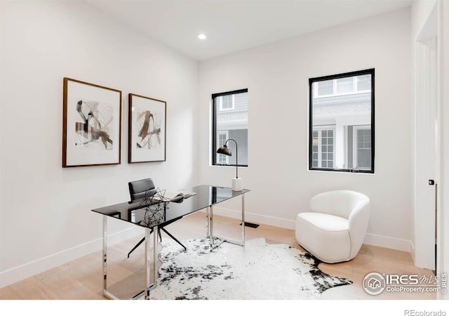 home office with light hardwood / wood-style flooring