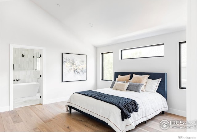 bedroom featuring lofted ceiling, ensuite bathroom, and light wood-type flooring